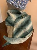 Shades of green and cream hand-knit shawl, with brass pin